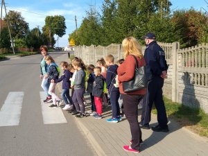 dzielnicowy uczy dzieci przechodzić przez przejście dla pieszych